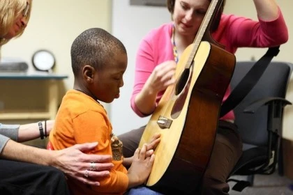 A music therapy session where a guitar teacher interacts with a boy with special needs