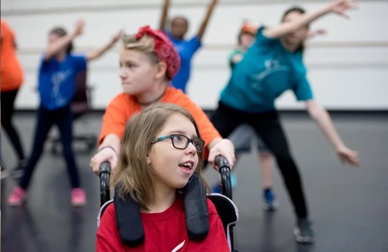 Image of a kid with cerebral palsy in a wheelchair captivating the audience with their talent and passion at a dance event
