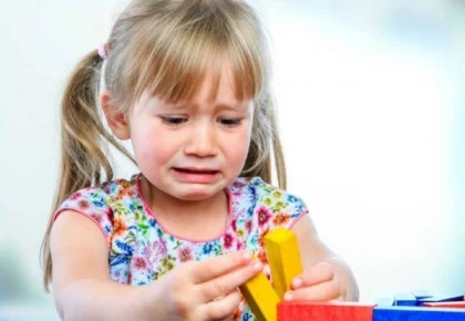 Baby girl experiencing sensory overload during playtime, a common challenge in sensory processing disorder