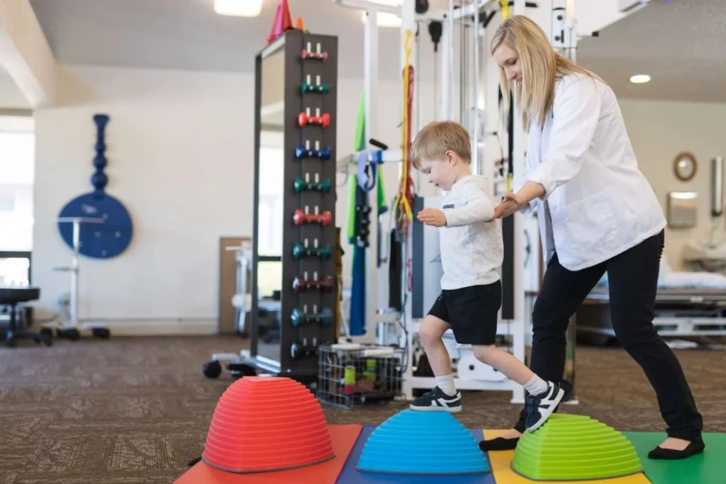 Image of a therapist providing guidance and support to a small boy during a physical therapy exercise