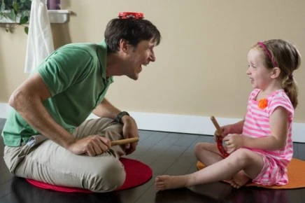 A father and his daughter with special needs having a joyful time playing an instrument together during a music therapy session