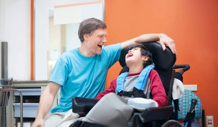 A boy with cerebral palsy and his compassionate doctor sitting together in wheelchairs