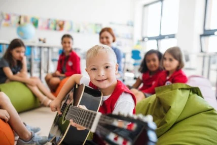 A child playing guitar in a classroom setting, fostering social skills development