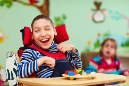 Image of a kid with cerebral palsy laughing, radiating happiness and pure joy