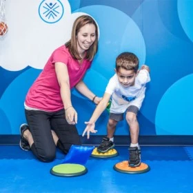 Image of a therapist providing encouragement and support to a small boy during a physical therapy exercise